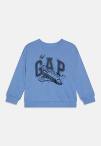 Modrá mikina s černou grafikou raketoplánu a slovem "GAP" spolu s planetami, vyrobená z měkké tkaniny s žebrovanými manžetami.