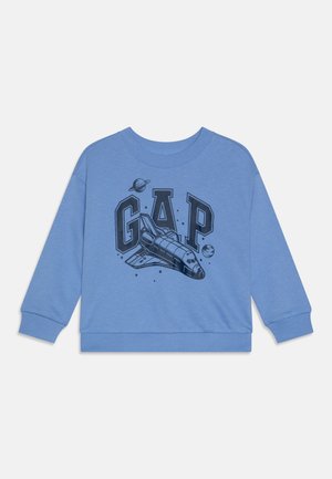 Modrá mikina s černou grafikou raketoplánu a slovem "GAP" spolu s planetami, vyrobená z měkké tkaniny s žebrovanými manžetami.