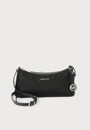 Sac bandoulière noir Michael Kors avec fermeture éclair argentée, sangle réglable et pendentif rond avec le logo MK sur fond blanc.