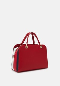 Sac à main texturé rouge avec des finitions en or, deux poignées et des côtés contrastés blancs et bleu marine. Forme rectangulaire avec fermeture à zip.