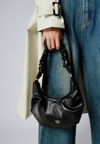Sac à main en cuir noir avec une poignée froncée, pr�ésentant une texture lisse et un petit accent logo doré à l'avant.