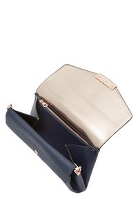 Granatowa skórzana torba o fakturowanej powierzchni, ze złotymi akcentami, otwartym wierzchem i licznymi przegródkami, w tym zapinaną na zamek sekcją wewnętrzną.