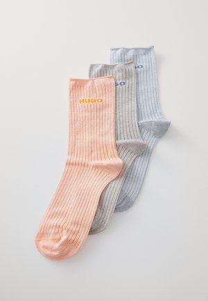 Three pairs of ribbed socks in orange, light gray, and light blue. Each features a logo on the upper section. Soft texture, casual design.
