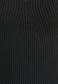 Černá žebrovaná pletenina s vertikálními pruhy. Textura je měkká, s výraznými liniemi vytvářejícími vlnitý vzor po celé délce.