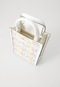 Tote-taske med en struktureret flerfarvet vævet yderside, hvide læderhåndtag og et lille mærke på forsiden, med et struktureret design.