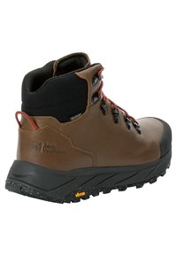 Scarpa da trekking marrone con colletto nero, lacci arancioni e suola testurizzata. Realizzata in materiale impermeabile e dotata di punta rinforzata. Brandizzazione Vibram visibile.