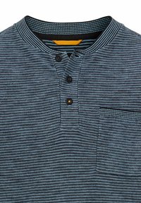 Gestreiftes Henley-Shirt in Dunkelblau und Grau. Mit einer Dreiknopf-Leiste, Brusttasche und geripptem Kragen. Baumwollstoff mit weicher Textur.
