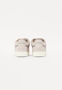 Béžové semišové tenisky s gumovou podrážkou, s hladkým povrchem a s vyraženým logem Reebok na patě. Klasický nízký design.