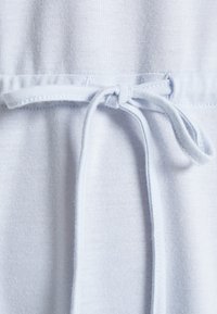 Tecido azul claro com uma textura suave, apresentando um cordão atado na cintura para ajuste. Design simples com detalhes mínimos.