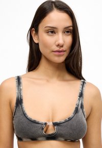 Μπικίνι τοπ με μαύρες και γκρι ρίγες από υφασμάτινη υφή, με στρογγυλή λαιμόκοψη και άνοιγμα στο κέντρο με ασημένια διακοσμητική λεπτομέρεια.