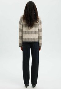 Villane segu ja heledate ja hallide horisontaalsete triipudega lühikese lõikega sviiter, kombineeritud kõrge vöökohaga tumedate teksadega. Kootud tekstuur ja sobivate varrukatega.