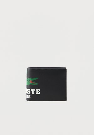 Sort læderpung med en glat tekstur, der har et grønt krokodillelogo og hvid tekst "LACOSTE PARIS" på forsiden. Kompakt bi-fold design.