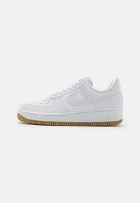 Bílé tenisky Nike Air Force 1 s texturovaným svrškem, šněrovacím designem a podešví z gumy. Výrazný detail swoosh na boku.