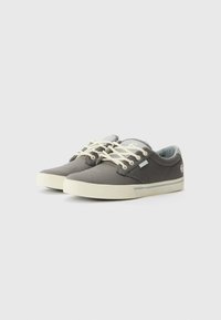 Canvas sneakers in dark grey with cream laces and a white sole. Features a ribbed texture and subtle branding on the side.