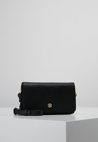 Černá kožená kabelka přes rameno se zlatými detaily, plochým designem a popruhem. Na přední straně se nachází malý květinový akcent s logem.