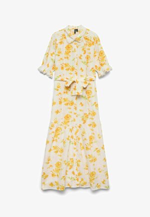 Blomstret kjole med gule og oransje blomster på hvit bakgrunn. Har kragehals, korte volangermser og midjebånd.