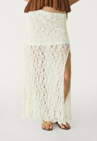 Blond maxikjol i off-white med hög slits, som har ett texturerat öppet mönster, mjukt tyg och resårmidja.
