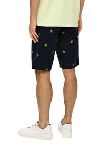 Marineblau kurze Hosen mit grüner Blattstickerei, aus weichem Stoff gefertigt. Bietet eine lockere Passform und gesäumte Kanten. Kombiniert mit weißen Sportschuhen.
