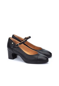 Chaussures Mary Jane noires avec un petit talon carré, présentant un capuchon en cuir lisse et un panneau latéral en tissu texturé. Bride réglable avec boucle.