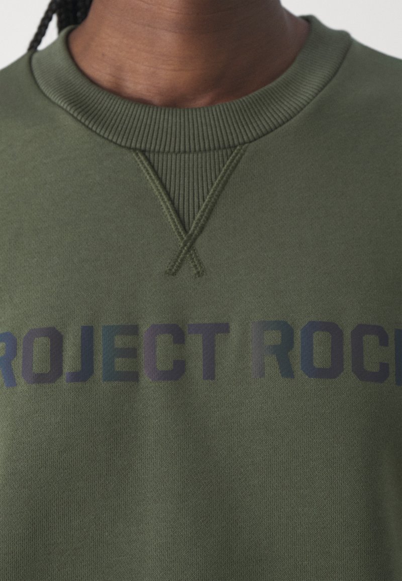 Grüne Sweatshirt mit geripptem Rundhalsausschnitt und strukturierten Akzenten. Zeigt "PROJECT ROCK" in kräftigen, kontrastierenden Farben. Weicher Stoff.