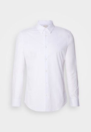 White long-sleeve button-up shirt in smooth fabric, featuring a classic collar, front buttons, and subtle logo on the chest.