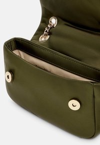 Borsa a tracolla in tessuto verde oliva con una superficie liscia, caratterizzata da accessori in metallo dorato e dettagli in catena. L'interno è rivestito in beige.