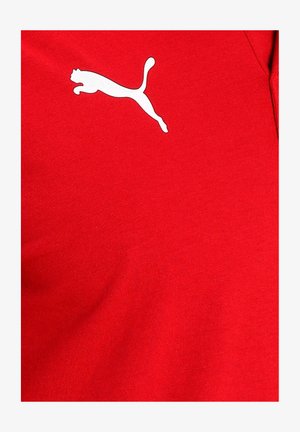 Rød stof t-shirt med et hvidt logo af en springende kat på venstre brystområde. Materialet ser glat ud med en tætsiddende design.