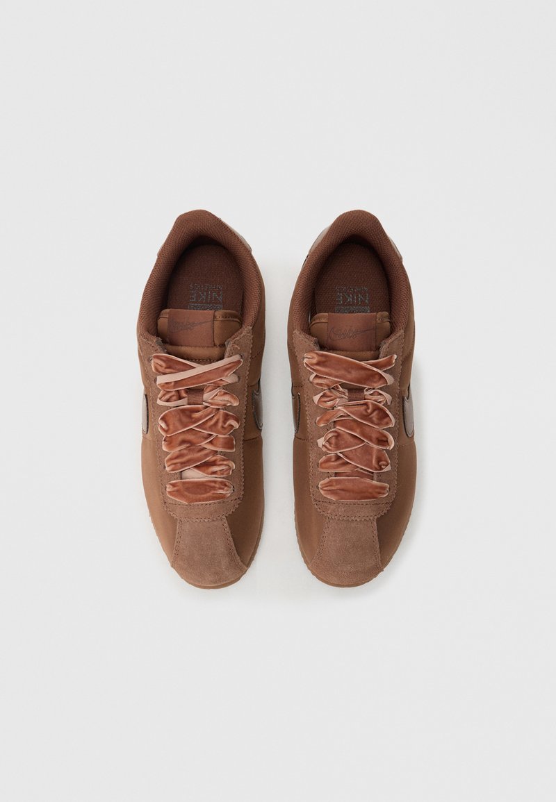 Brown athletic sneakers with a mix of suede and mesh, featuring wide laces and a smooth side logo, displayed from above.