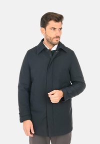 Cappotto blu scuro con collo a risvolto, tasche frontali e chiusura con zip. Realizzato in materiale morbido e resistente all'acqua, taglio aderente.