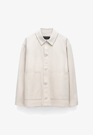 Beżowa, zapinana na guziki kurtka z długim rękawem, kołnierzem i dwoma dużymi przednimi kieszeniami, prezentowana na białym tle.