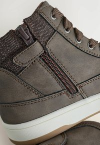 Brun hög sneakers av texturerat syntetmaterial, med en sidodragkedja, kontrasterande tygpanel och gummisula med grepmönster.