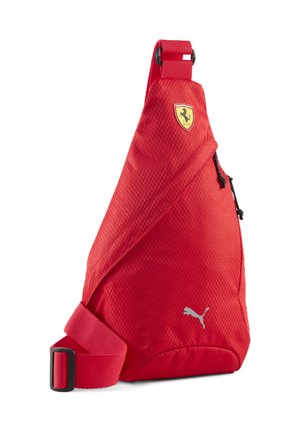 Rode slingrugzak met diagonale ritssluiting, Ferrari schildlogo bovenaan en zilverkleurig Puma-logo onderaan, verstelbare rode band.