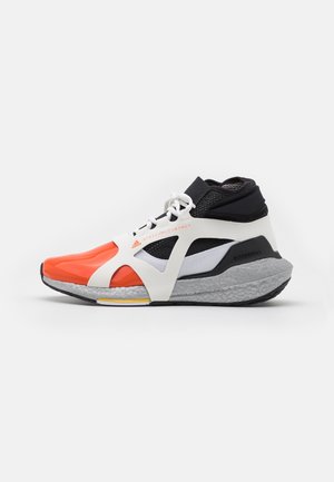 Sporty sneaker with orange toe, white and black mesh upper, white laces, and thick gray sole with textured design.