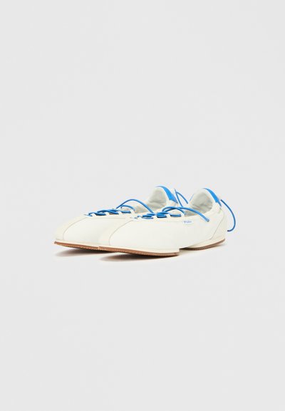 Καμβά παπούτσια σε ελεφαντόδοντο με μπλε λεπτομέρειες, με κομψό σχήμα, στρογγυλεμένη μύτη και λαστιχένια σόλα. Κορδόνια σε μπλε που ξεχωρίζουν.