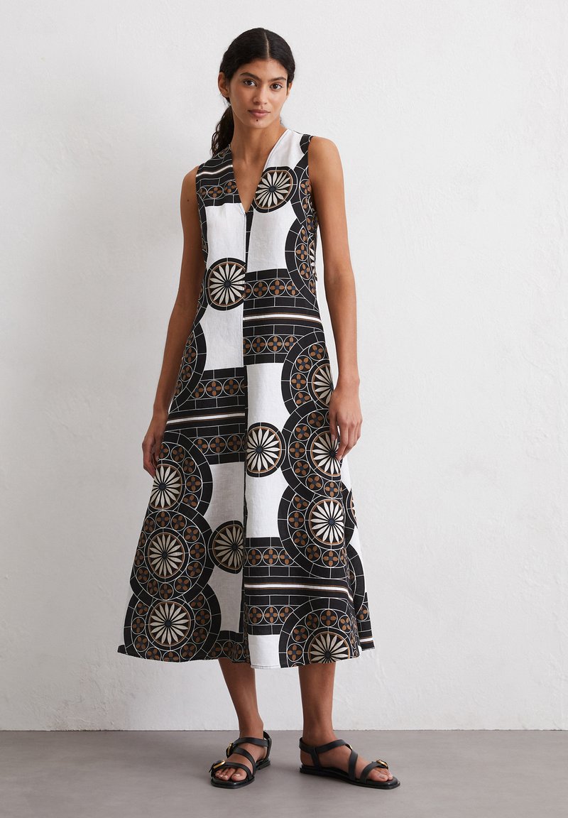 Robe sans manches noir et blanc avec des motifs circulaires et des designs géométriques. Fabriquée en tissu léger, au look décontracté et avec un décolleté en V.