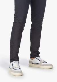 Vita och grå sneakers med marinblå accenter, med material av mocka och läder, rund tå, platt sula och snörningsdesign.