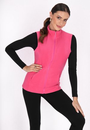 Vest din fleece de culoare roz strălucitor cu fermoar frontal, având un design ajustat, textură netedă și buzunare laterale, purtat peste un top negru și colanți.