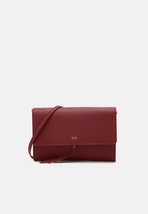 Red leather clutch bag with a slim design, featuring a flap closure and an adjustable shoulder strap. Logo embossed on the front.