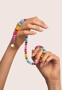 Bunte Perlenkette und Armband, die runde, glänzende Perlen in verschiedenen Farben zeigen, mit einem Verschlussdetail in Goldoptik an der Kette.