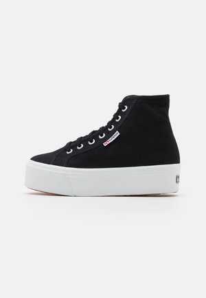 Schwarzer hoher Canvas-Sneaker mit weißer dicker Plateausohle und Schnürsenkeln, mit kleinem Superga-Logo an der Seite.