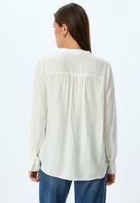 Witte lange mouwen shirt van lichtgewicht stof, met een geplooide achterkant met een subtiele textuur en knoopmanchetten. Casual fit.