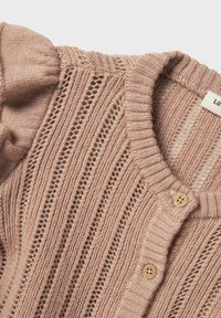 Cardigan en maille rose clair avec une texture côtelée, présentant des motifs à mailles ouvertes, des boutons en bois et un design à col rond.