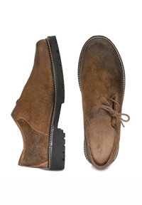 Braune Lederschuhe mit strukturiertem Finish, Schnürdetails und einer stabilen schwarzen Gummisohle mit einem gemusterten Profil.