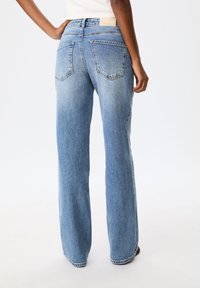 Jean large bleu clair en denim, doté de deux poches arrière et d'une taille mi-haute avec des détails mécaniques minimaux.