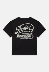 Camiseta de algodón negra con un gran texto vintage blanco en la parte posterior, incluyendo "Replay," "Desde 1981," y "Productos de Denim."