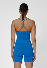 Blauw functioneel sportoutfit met een aansluitend top met dunne bandjes en high-waisted shorts, gemaakt van een gladde, elastische stof.