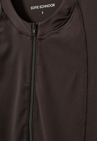 Čierna zipsová bunda vyrobená z hladkej tkaniny, s krátkym golierom, viditeľným zipsom a tónovým stehom pozdĺž švov. Veľkosť označená ako S.