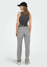 Grå tætsiddende tanktop parret med lysegrå lige ben-jeans. Outfittet inkluderer også en sort kasket og et kontrasterende bælte.