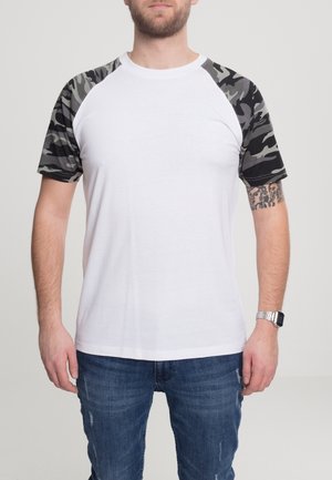 Hvid kortærmet T-shirt med sort og grå camouflage mønster på ærmerne. Rund hals, glat materiale, afslappet pasform.
