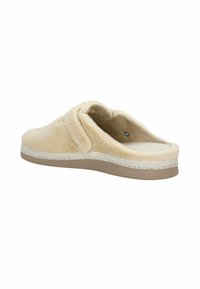 Beige slipper gemaakt van zacht, textuur materiaal met een gevoerde binnenzool. Heeft een ronde neus, open achterkant en een lichte zool met stiksel detail.